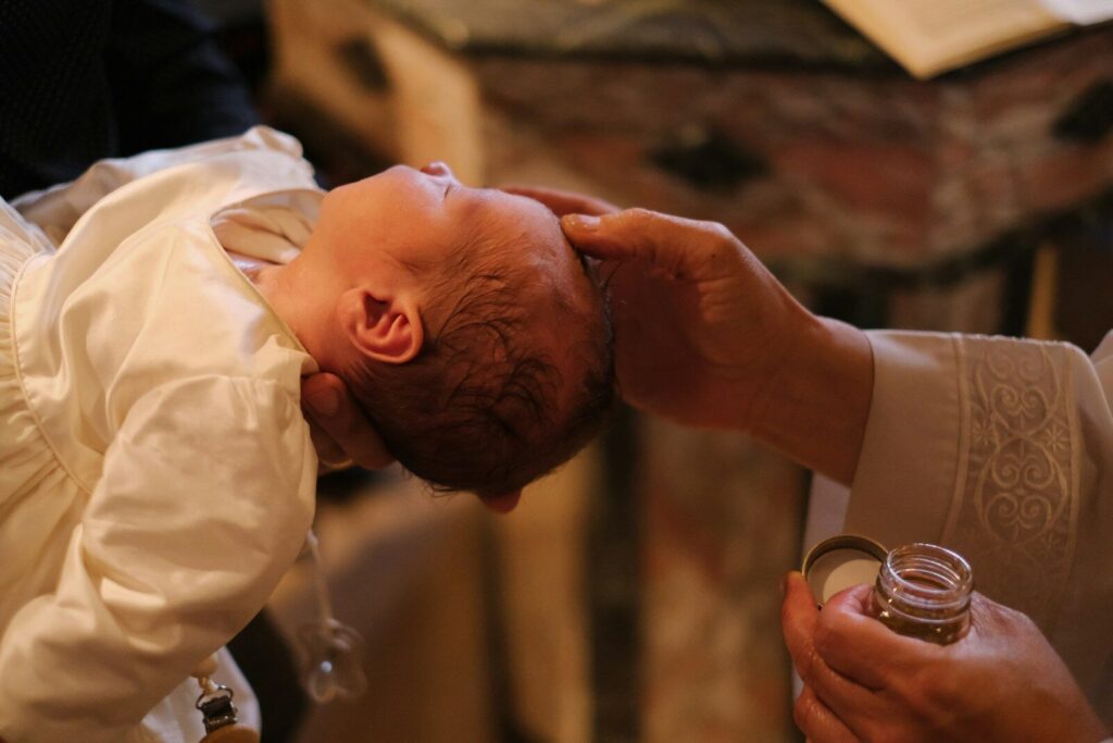 A baby is being held by a priest